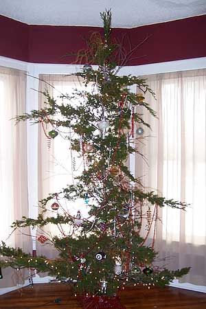 a small christmas tree sitting in the corner of a room next to two large windows