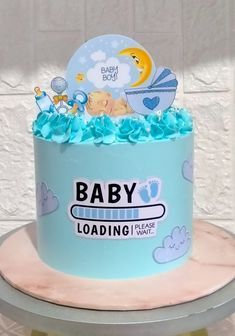 a baby shower cake with blue icing and decorations on top, sitting on a table