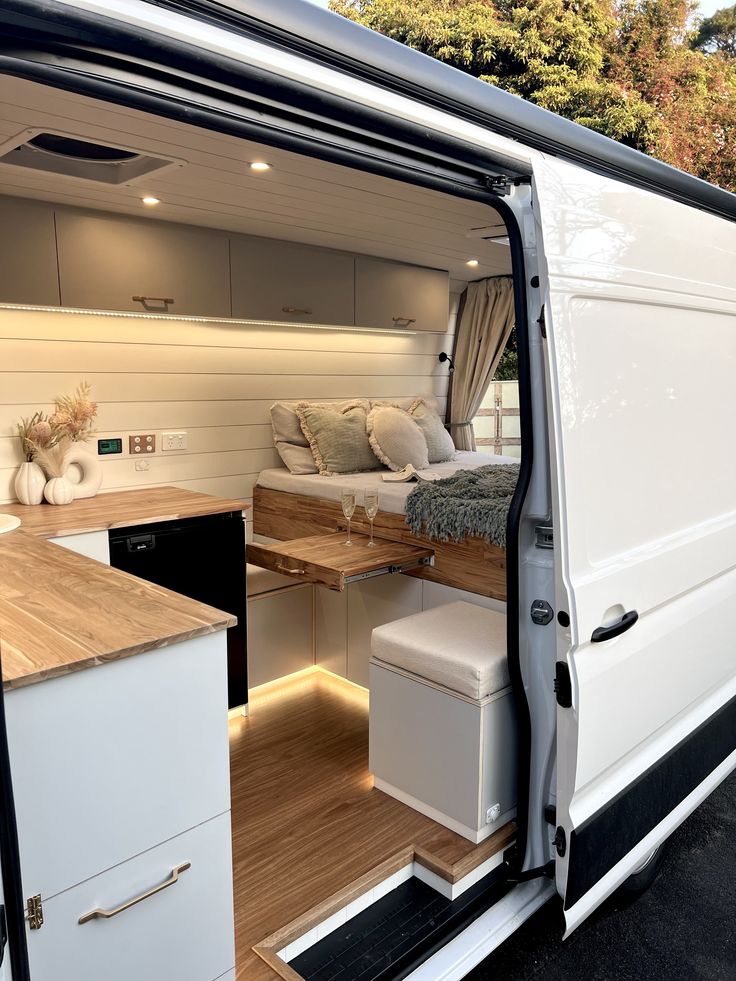 the interior of a camper van with its door open to reveal a kitchen and living area