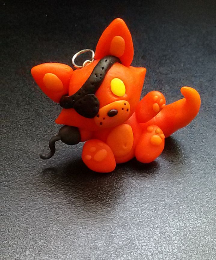 an orange plastic animal keychain sitting on top of a black table with a metal ring in it's mouth