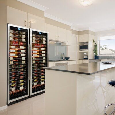 a kitchen with an island and two refrigerators in the middle, one has wine bottles on it