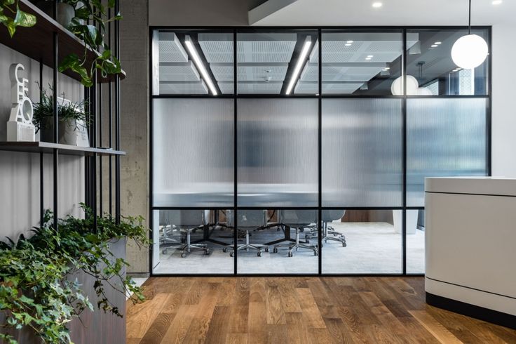 an office with glass walls and wooden floors