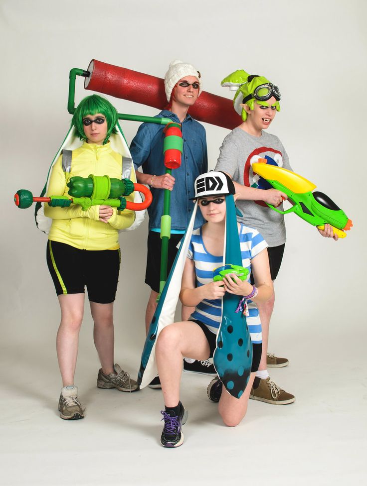 four people dressed in costumes posing for a photo with one person holding an object and the other wearing a hat