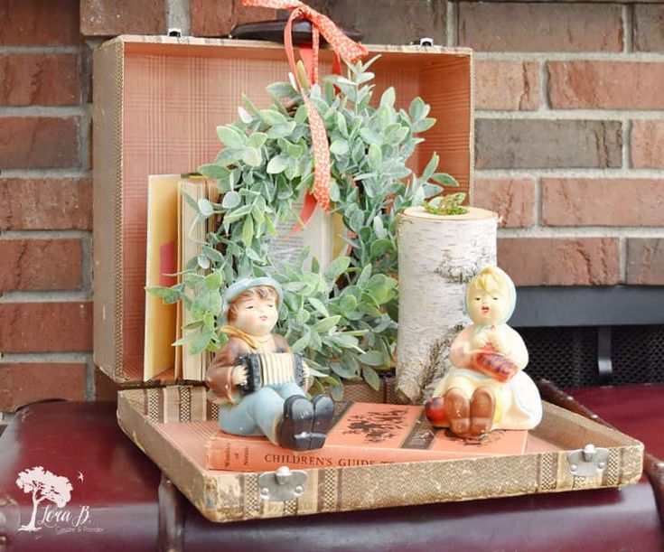 an old suitcase with some figurines on it and a plant in the back