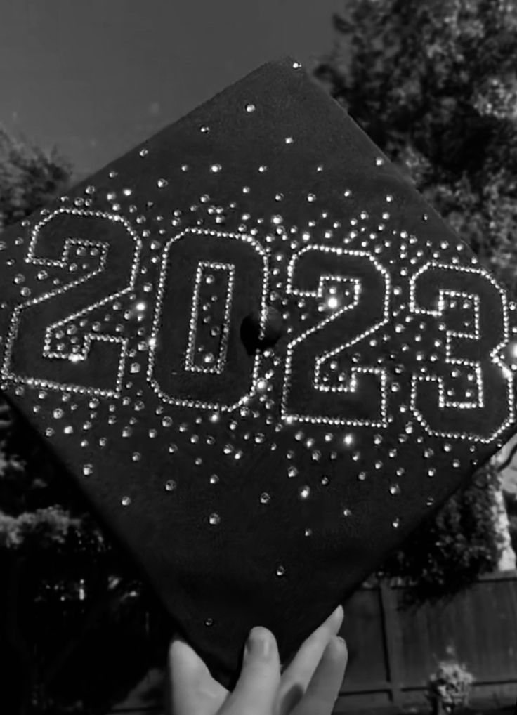 a black and white photo of someone holding up a graduation cap with the word boss on it