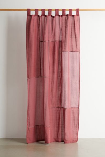 a pink curtain hanging on a wooden rod in front of a white wall and floor