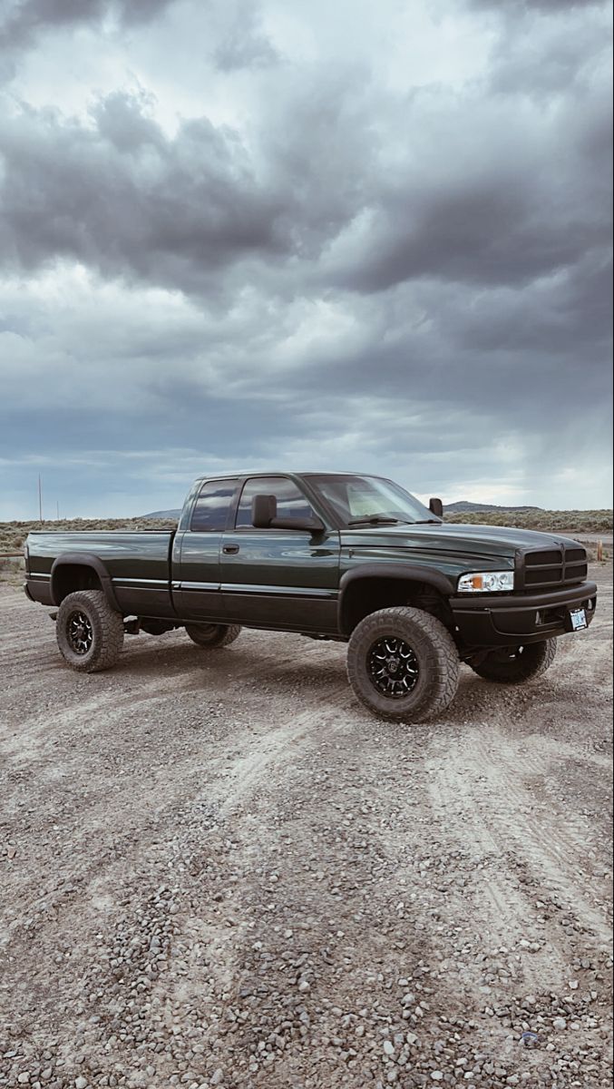 a black pickup truck parked on top of a dirt field