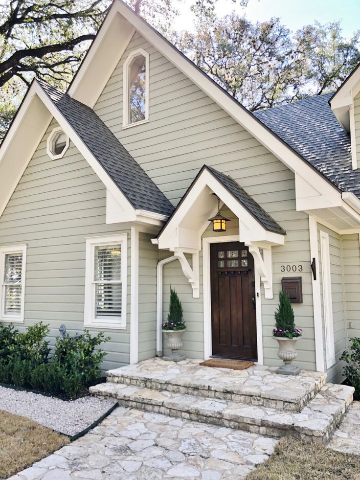 a gray house with white trim and stone steps