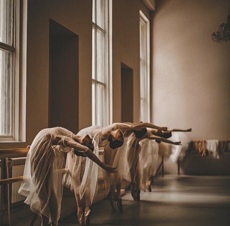 several ballet dancers in white tutus and veils are lined up on the floor