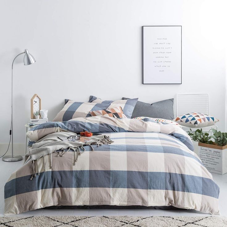 a bed with blue and white checkered comforter in a room next to a plant