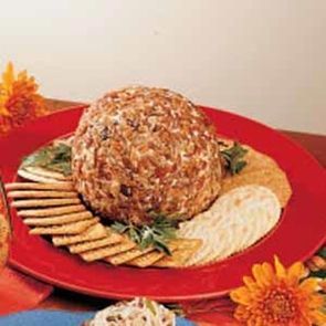 a cheese ball sitting on top of a red plate next to crackers and sunflowers