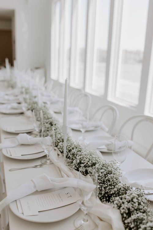 the table is set with white plates and place settings