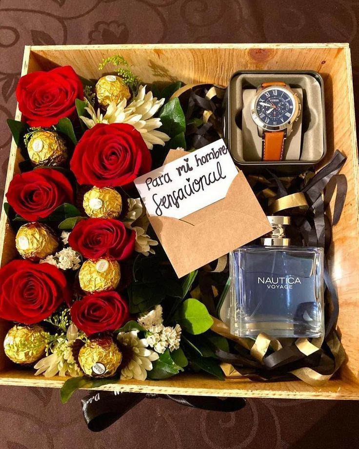 a wooden box filled with lots of red roses and chocolates next to a watch