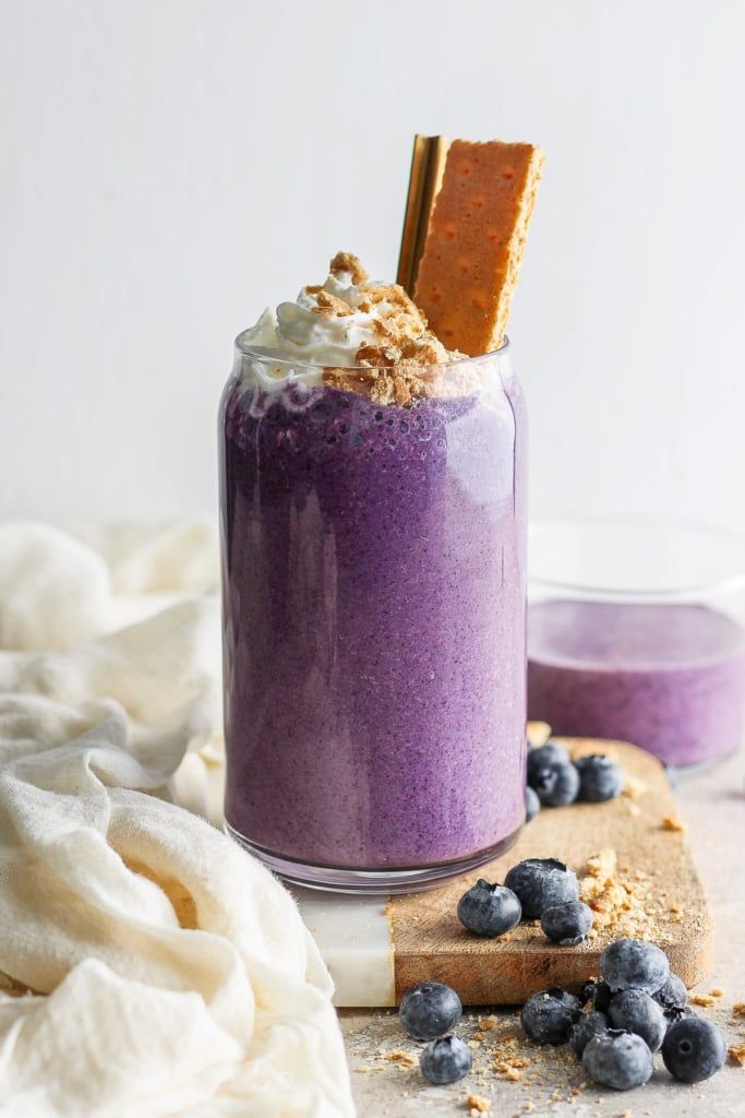 blueberry smoothie in a glass with graham crackers on top