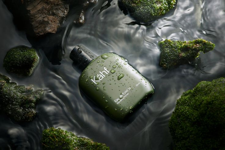 a bottle that is sitting in the water next to some rocks and mossy plants