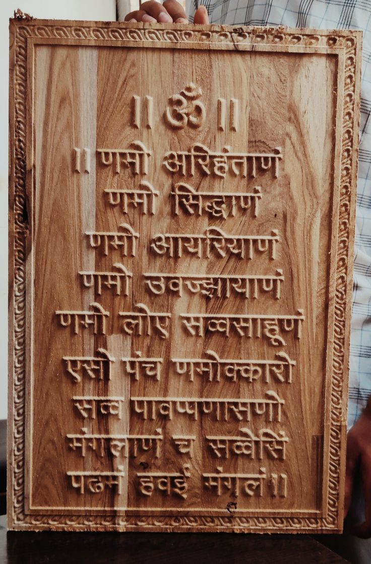 a person holding up a wooden plaque with writing on it