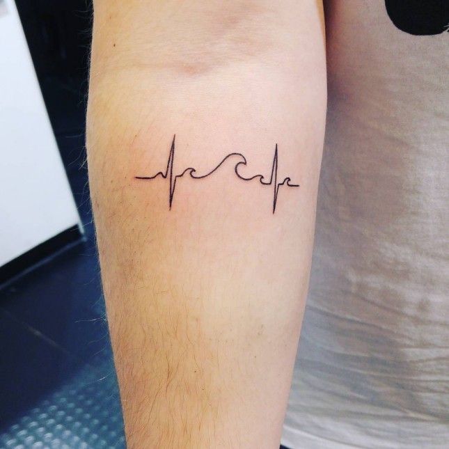 a person with a tattoo on their arm has a heartbeat and the word love written in cursive lines