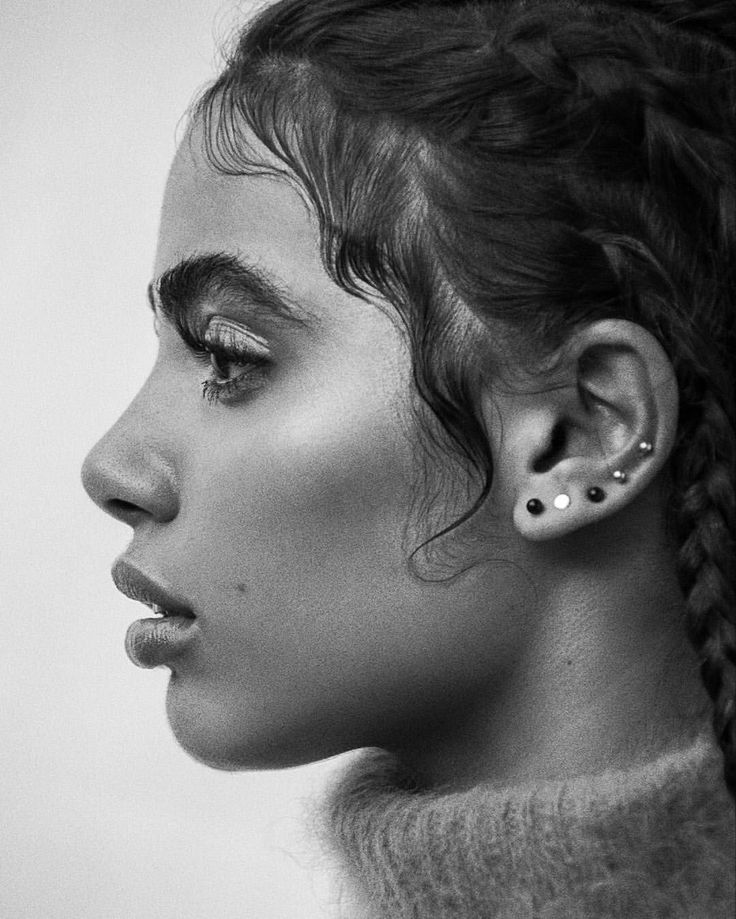 black and white photograph of a woman with ear piercings on her ears, looking to the side