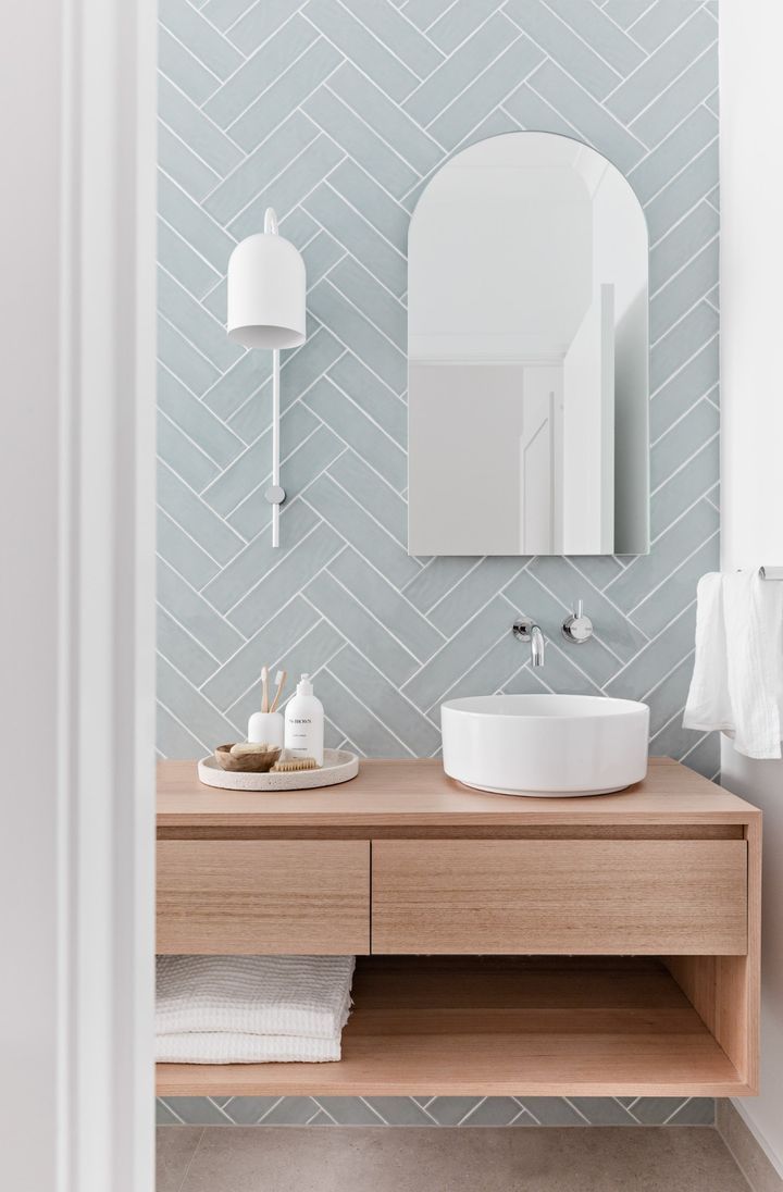 a bathroom with a sink, mirror and towel on the shelf in front of it