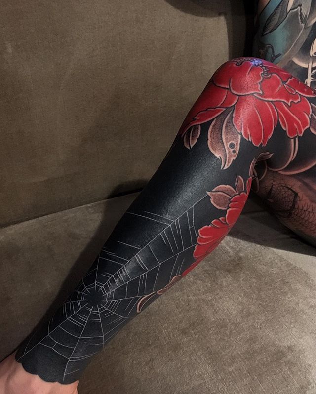 a woman's leg with tattoos on it and a red flower in the center