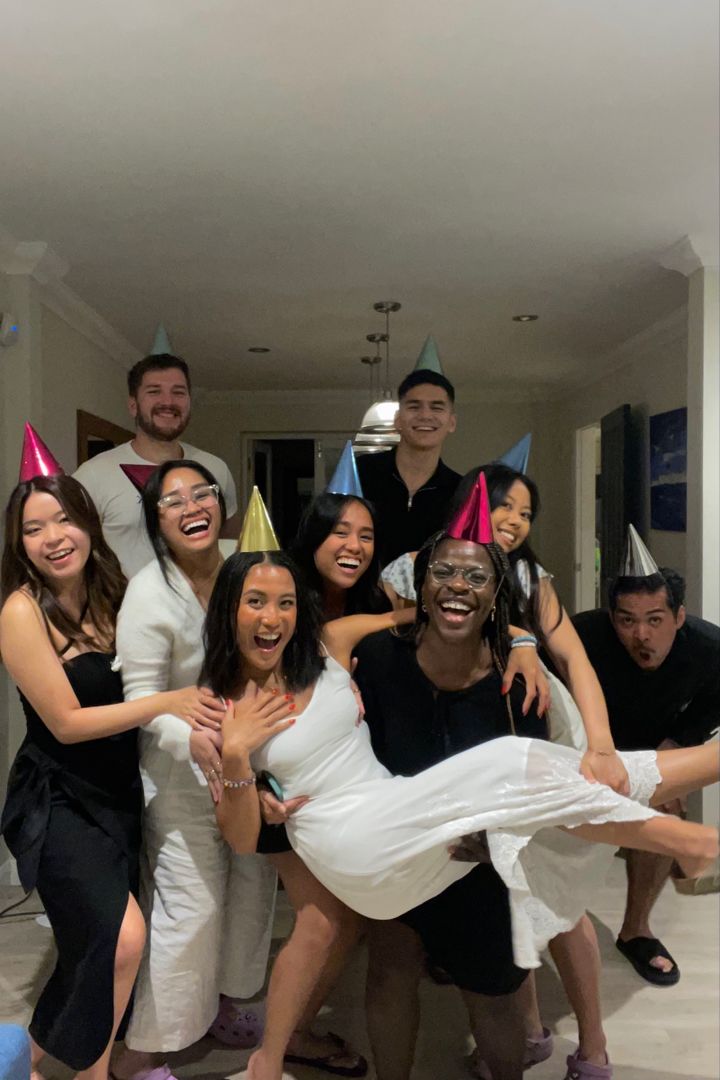 a group of people in party hats posing for a photo with one woman on her back