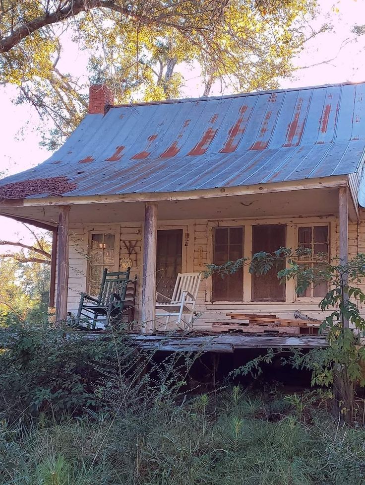 an old run down house with rocking chairs on the porch