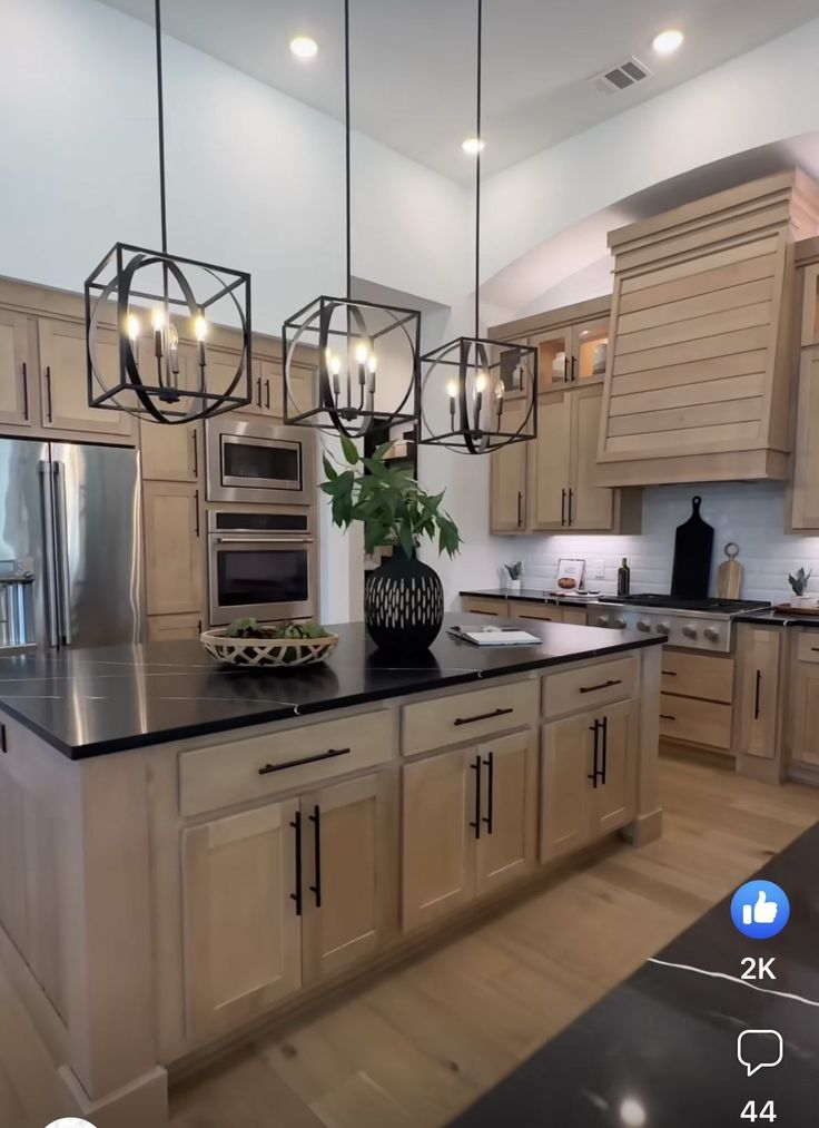 a large kitchen with wooden cabinets and black counter tops is shown in this image, there are lights hanging from the ceiling