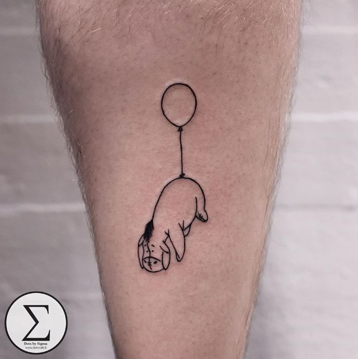 a small black and white tattoo of a hand holding a balloon on the leg with a dog's head