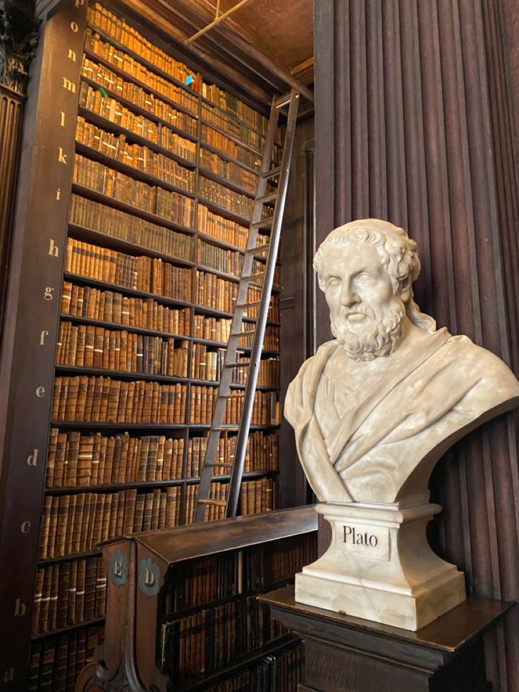 a busturine in front of a bookcase filled with books