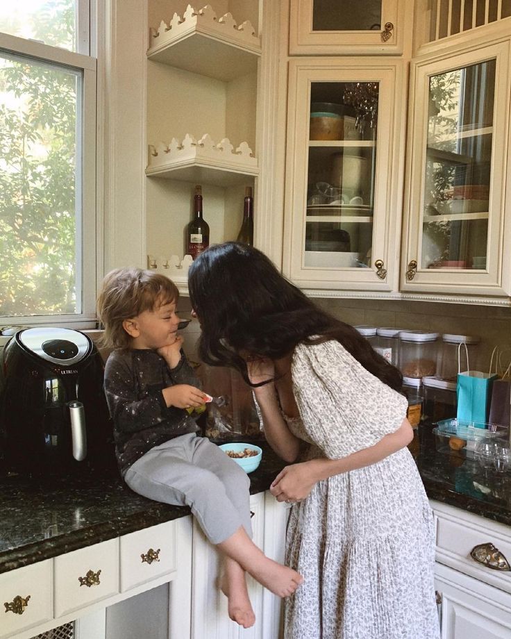 two young children are sitting on the counter and one is eating food from a bowl