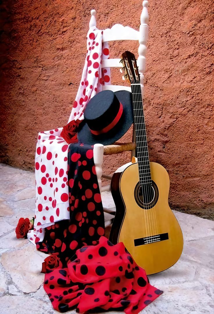 a guitar, hat, and scarf are sitting on the ground next to a wall