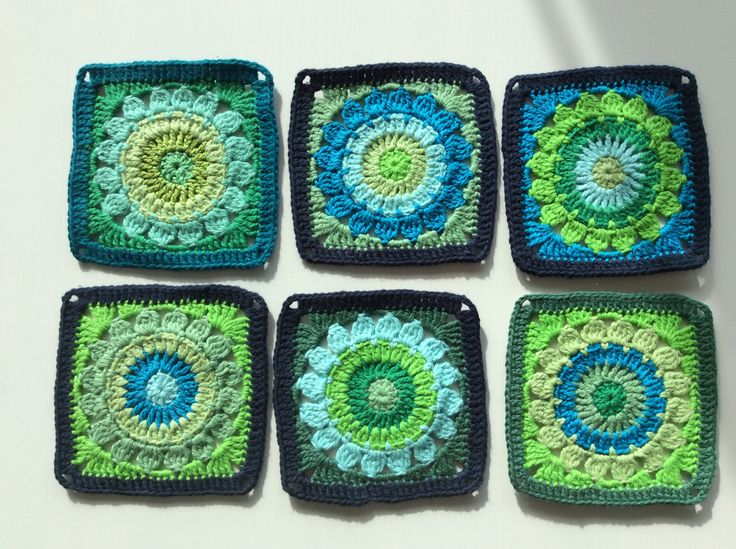 six square crocheted coasters with green and blue designs on them sitting on a white surface