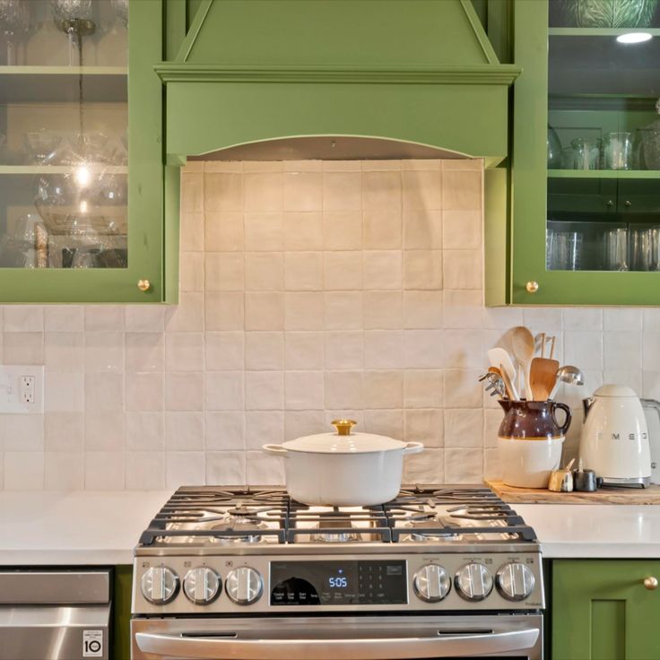 a stove top oven sitting inside of a kitchen next to green cabinets and counter tops