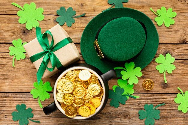 a green hat and some gold coins in a bowl on a wooden table with shamrocks