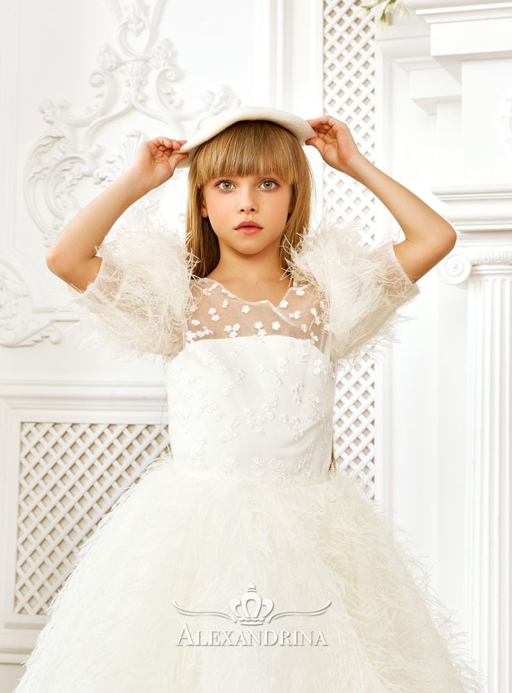 Stylish outfit in white with decorative flowers and feathersWonderful midi dress in white. The transparent bodice along the tight corset has a V-neckline and a zipper in the back, and is decorated with lace flowers in the front. Puffy lantern sleeves are decorated with long airy feathers. The bell skirt is also all embroidered with feathers, and the shape is kept thanks to the wide chorus at the bottom. #flowergirldress #communiondress #weddingdress #beautypageant White Dresses With Sheer Sleeves And Fitted Bodice, Wedding Dress With Feather Trim And Fitted Bodice, Elegant White Feathered Dress, Fitted Lace Dress With Feather Trim, Spring Tulle Dress With Feather Trim, Elegant Tulle Dress With Feathers, White Tulle Dress With Sheer Bodice, White Dress With Sheer Sleeves And Sweetheart Neckline, White Organza Dress With Sheer Sleeves