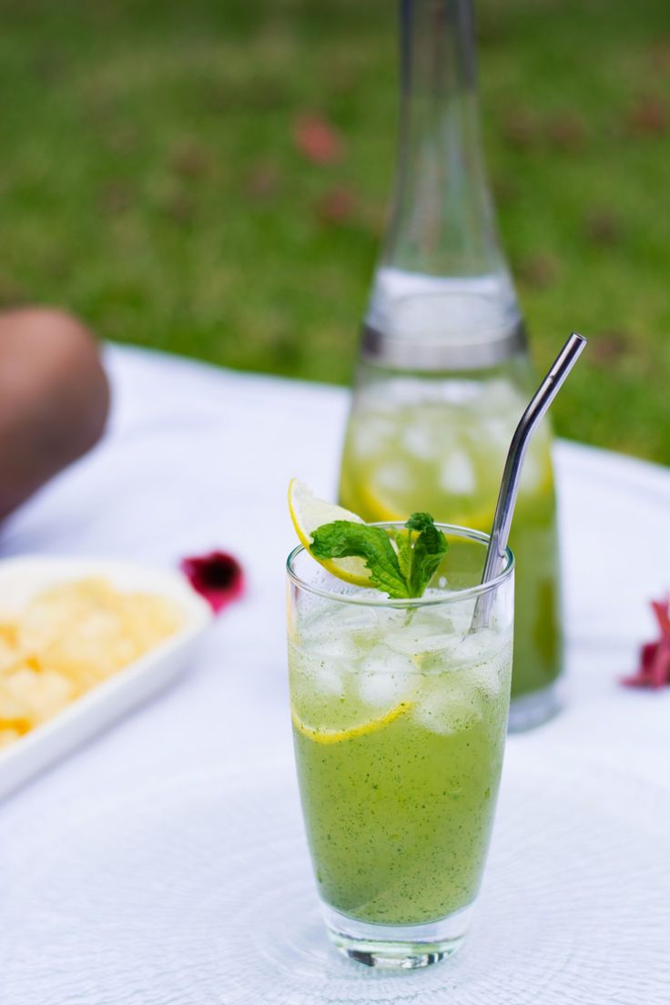 a glass filled with green liquid sitting on top of a table