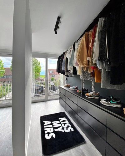 a walk in closet with lots of clothes and shoes on the shelves next to it