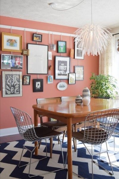 a dining room table with chairs and pictures on the wall