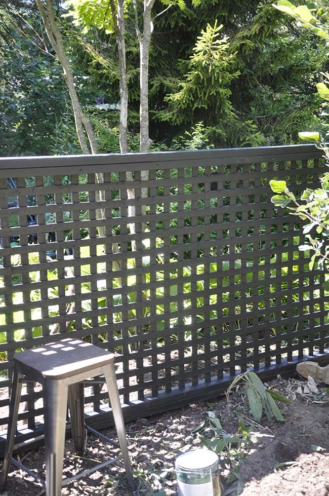 a wooden bench sitting in the middle of a yard next to a fence and trees