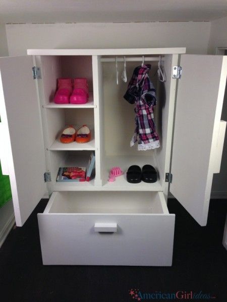 an open white cabinet with shoes and other items on it in a room that has black carpeting