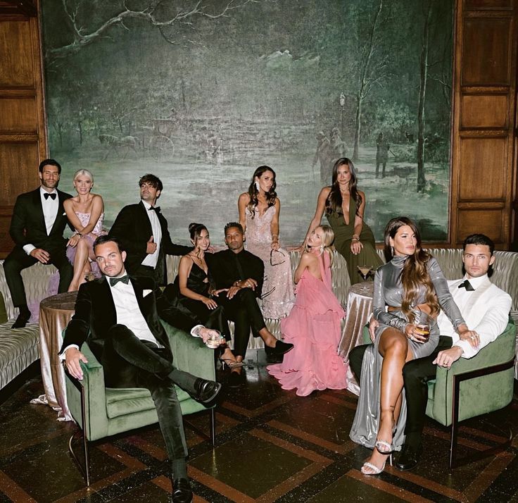 a group of people sitting on couches in front of a green wall with trees