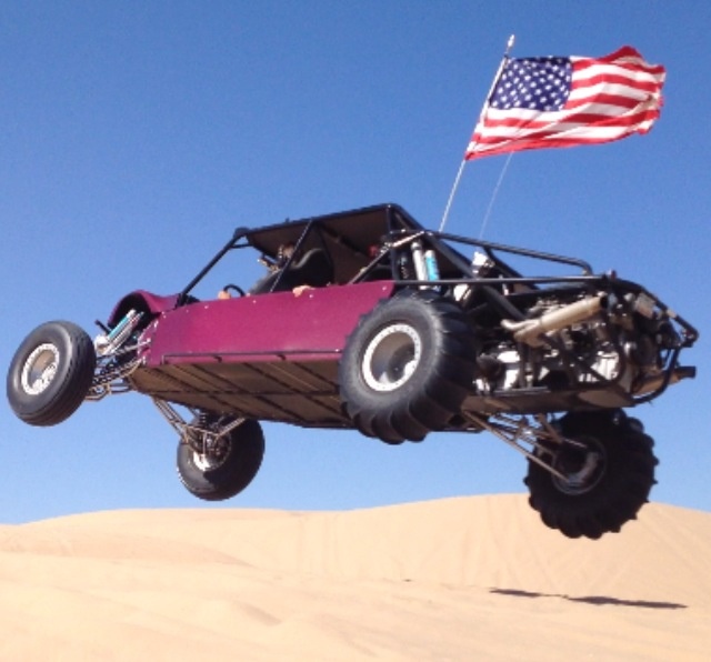 a pink buggy in the desert with an american flag on top