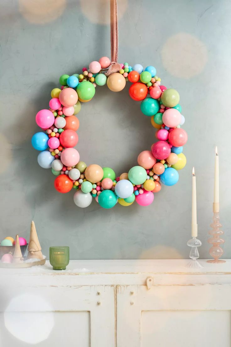 a wreath is hanging on the wall next to a white cabinet with candles and other decorations