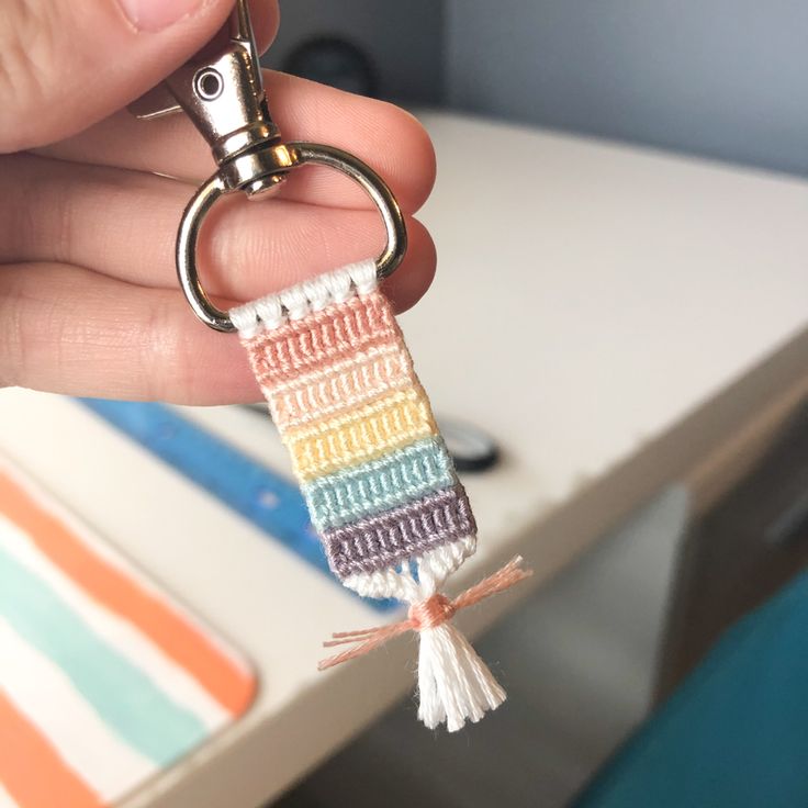 a hand holding a keychain with a multicolored stripe design on it