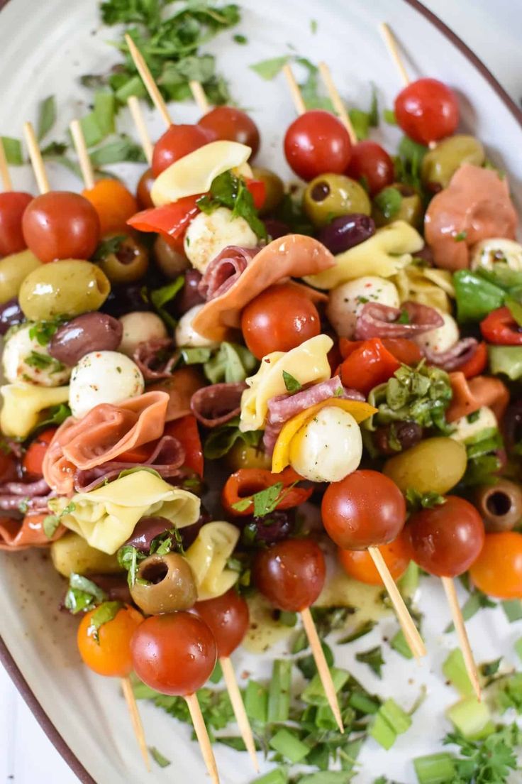 a white plate topped with lots of different types of food on skewered sticks