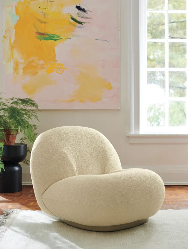 a white chair sitting on top of a rug in front of a window next to a potted plant