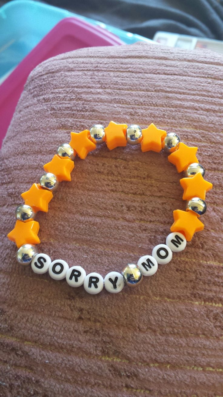 an orange and white bracelet that says sorry on it