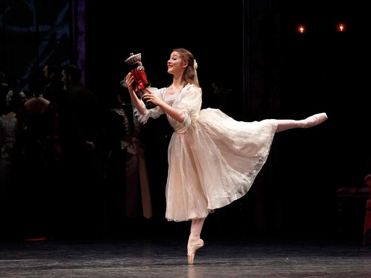 a young ballerina is performing on stage with her leg in the air while holding a red object