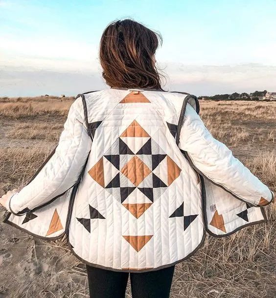 a woman standing in a field wearing a quilted jacket