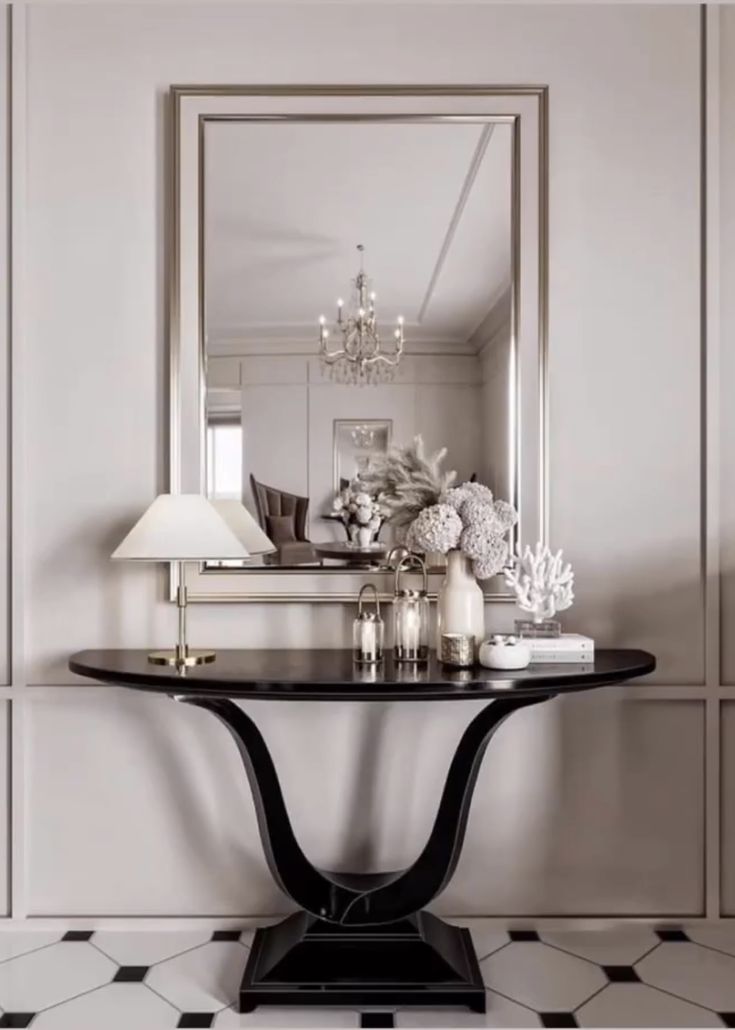 a black and white table with a mirror on the wall next to some vases